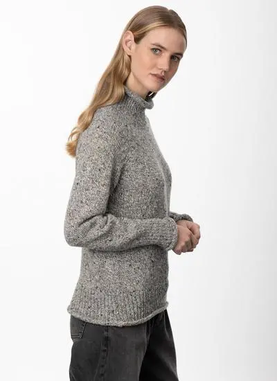 side angle studio shot of blonde woman wearing grey sweater