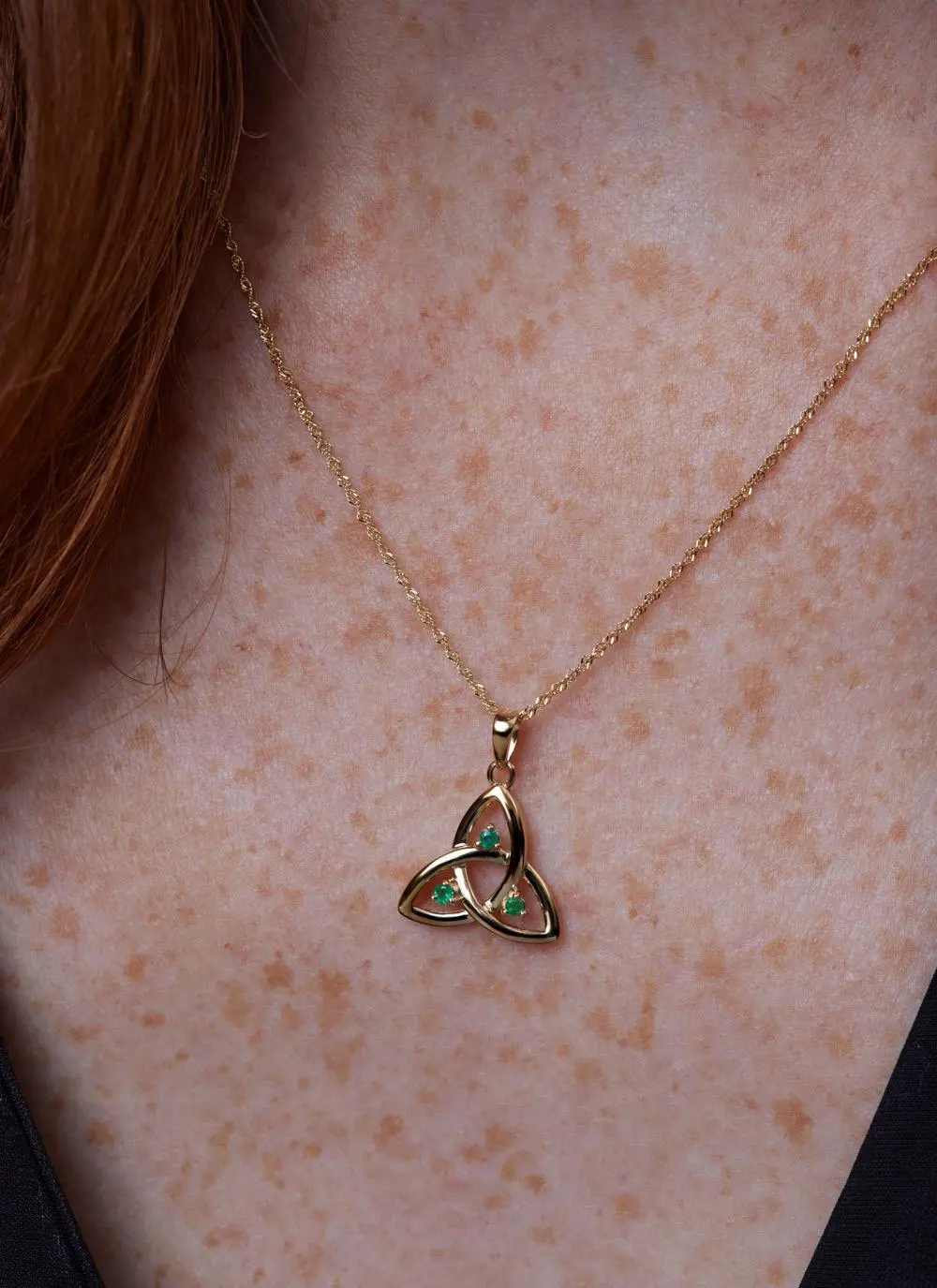 Decolletage shot of 14ct Gold Emerald Trinity Knot Pendant