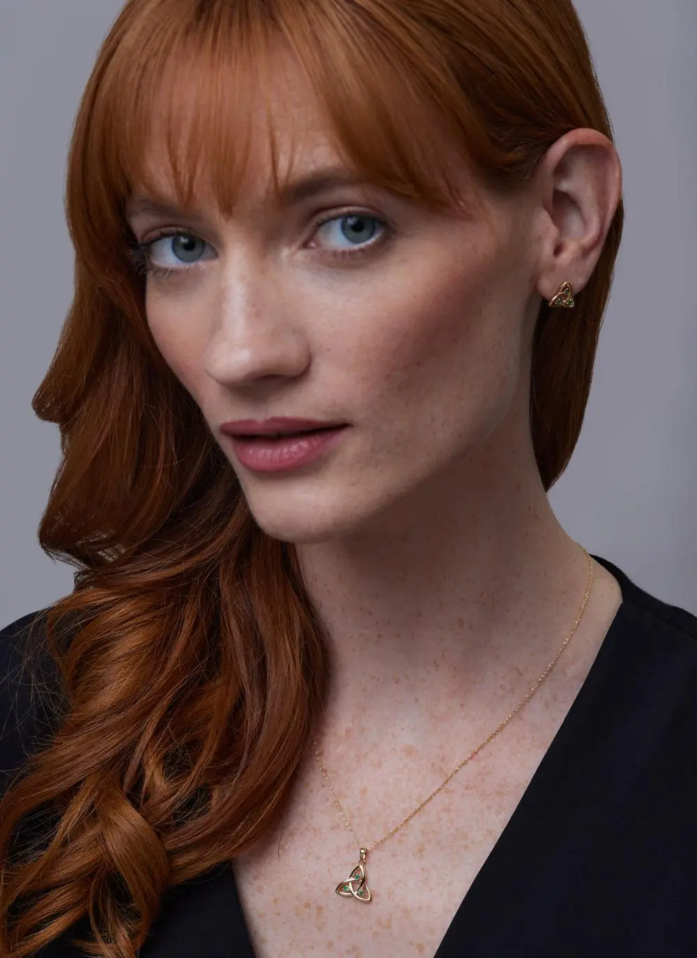 Red haired model wearing 14ct Gold Emerald Trinity Knot Pendant and matching earrings