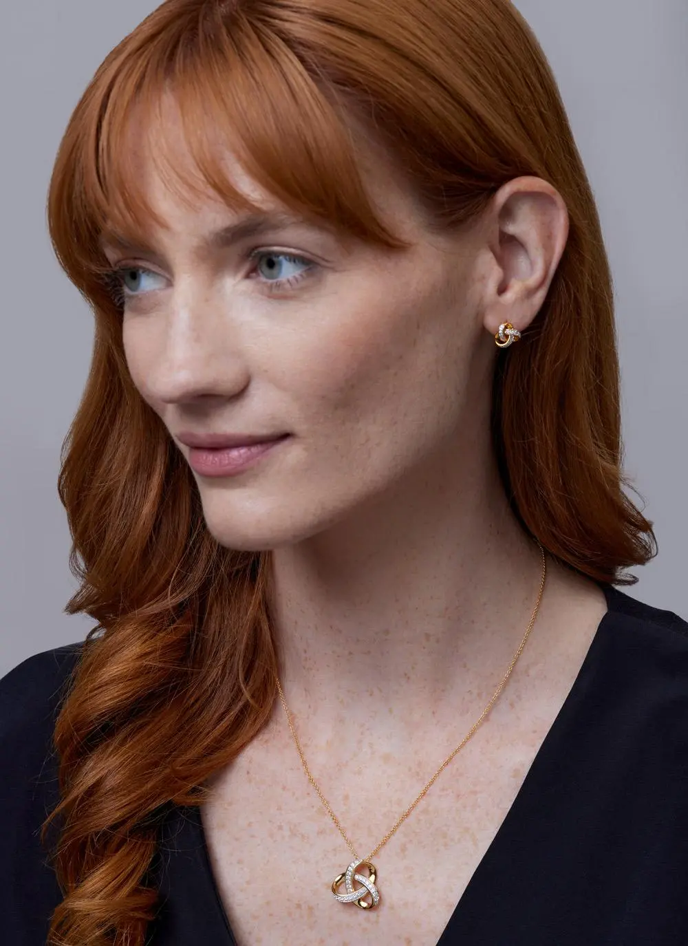 Red haired model wearing 14ct Gold Vermeil Trinity Knot Stud Earrings with Cubic Zirconia with matching pendant 