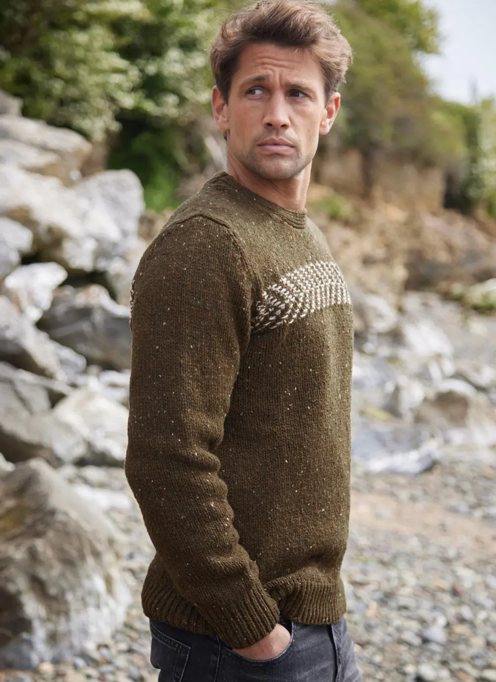 Man on beach wearing two tone crew neck sweater, side profile