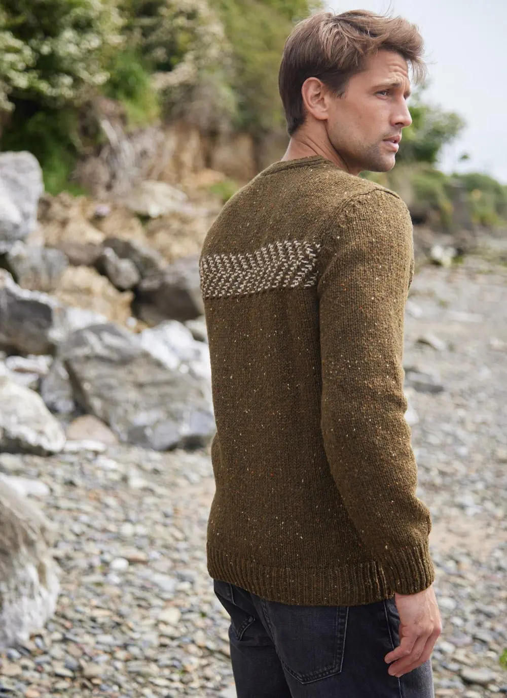 Man on beach wearing two tone crew neck sweater, back shot