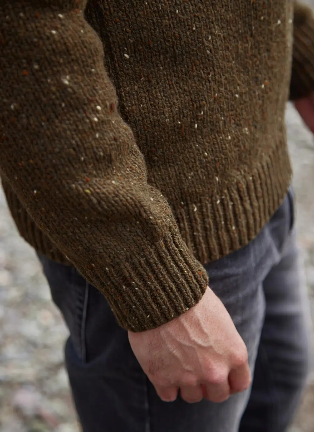 Man on beach wearing two tone crew neck sweater, cuff close up