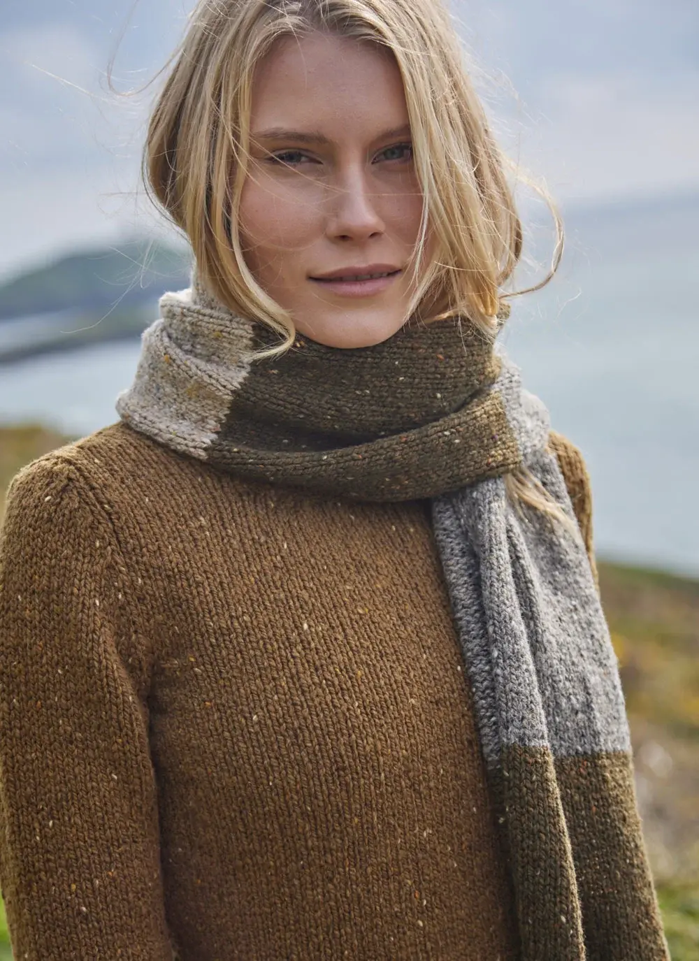 Woman wearing woolen brown toned scarf with sea in background
