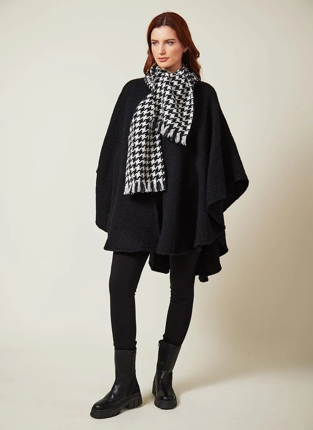 Full length studio shot of auburn haired woman wearing black wool cape with houndstooth scarf.