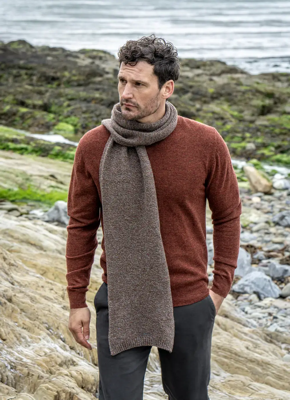 Personalized cashmere wool scarf in hazel brown, made in Ireland, styled with rust sweater and coastal backdrop