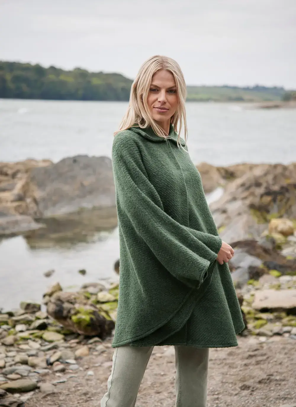 Blonde woman on beach in green cape made in ireland