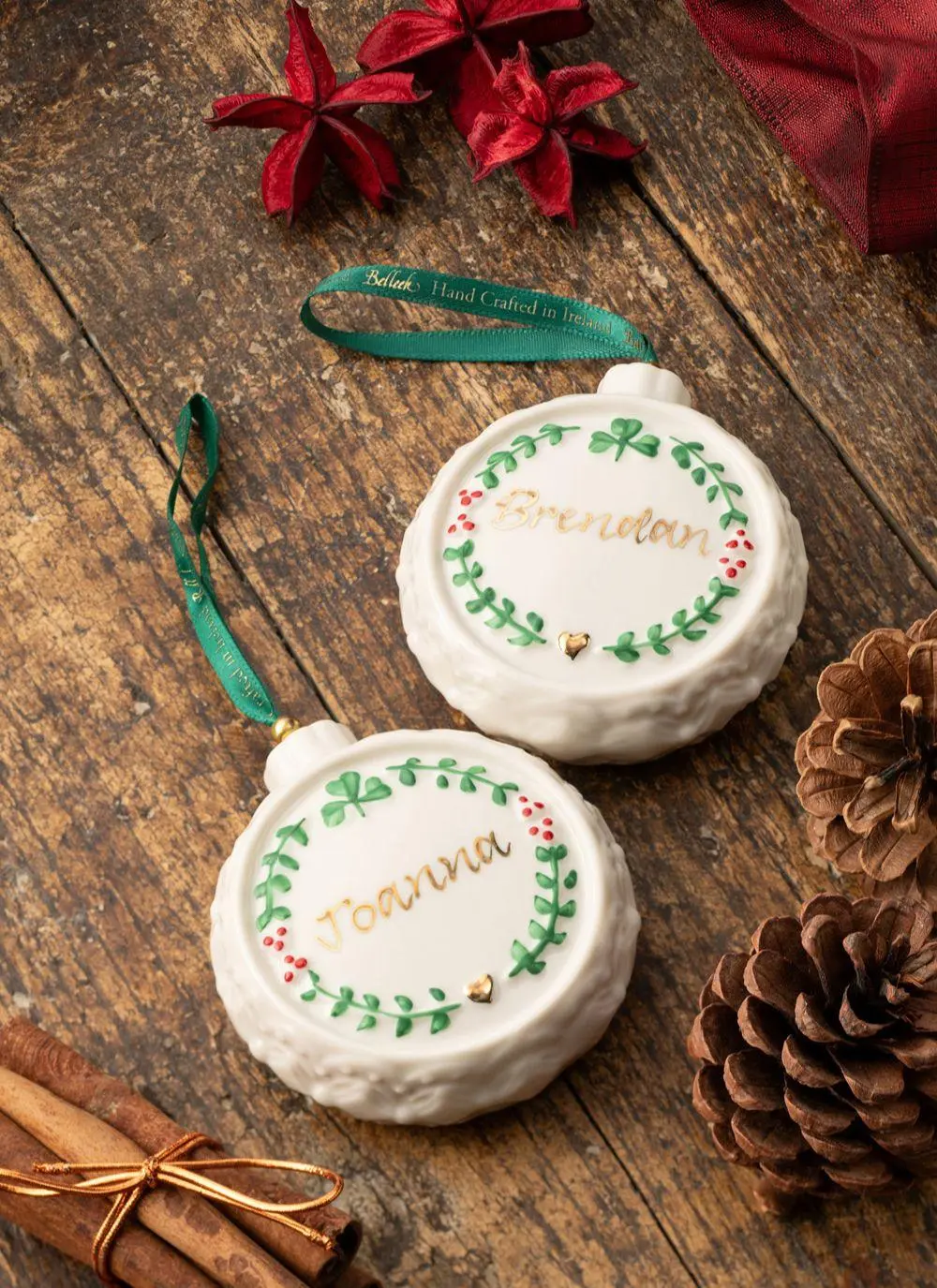 Two personalized christmas ornaments on a wooden table, decorated with names 