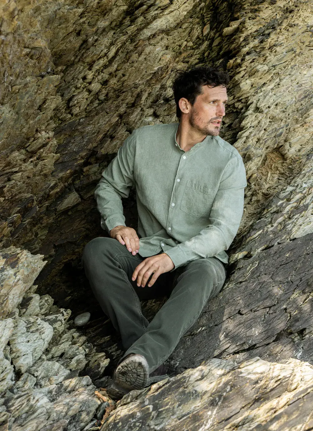 Donal cotton linen grandfather shirt in sage green, button-down front, lightweight and breathable, worn against rocky coastal backdrop