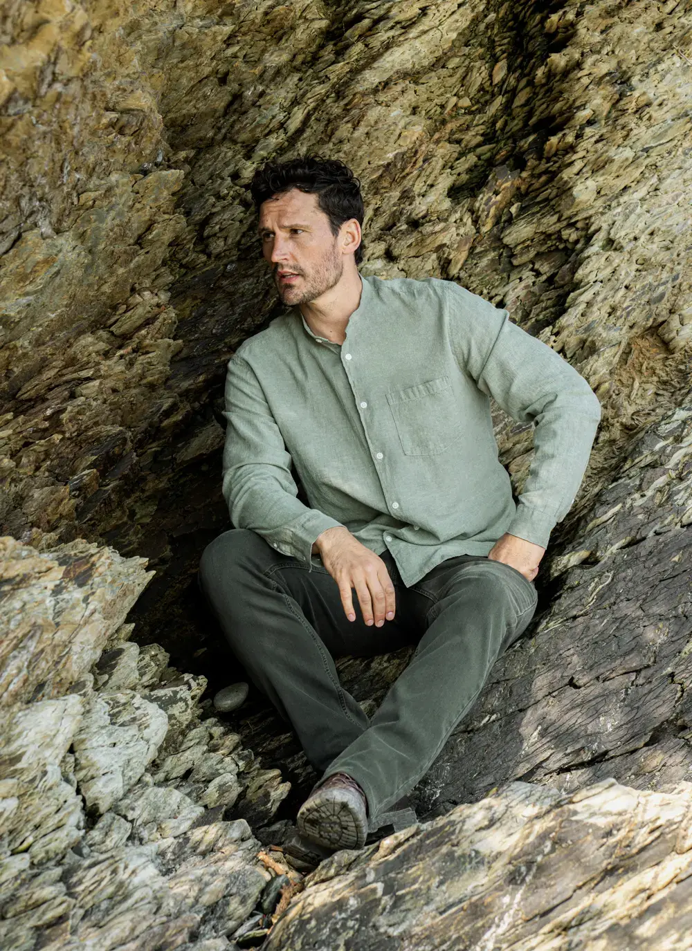 Donal cotton linen grandfather shirt in sage green, button-down front, lightweight and breathable, worn against rocky coastal backdrop