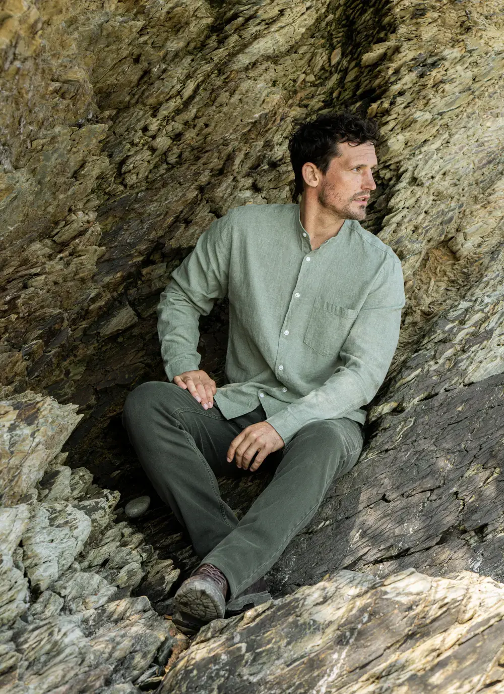 Donal cotton linen grandfather shirt in sage green, button-down front, lightweight and breathable, worn against rocky coastal backdrop