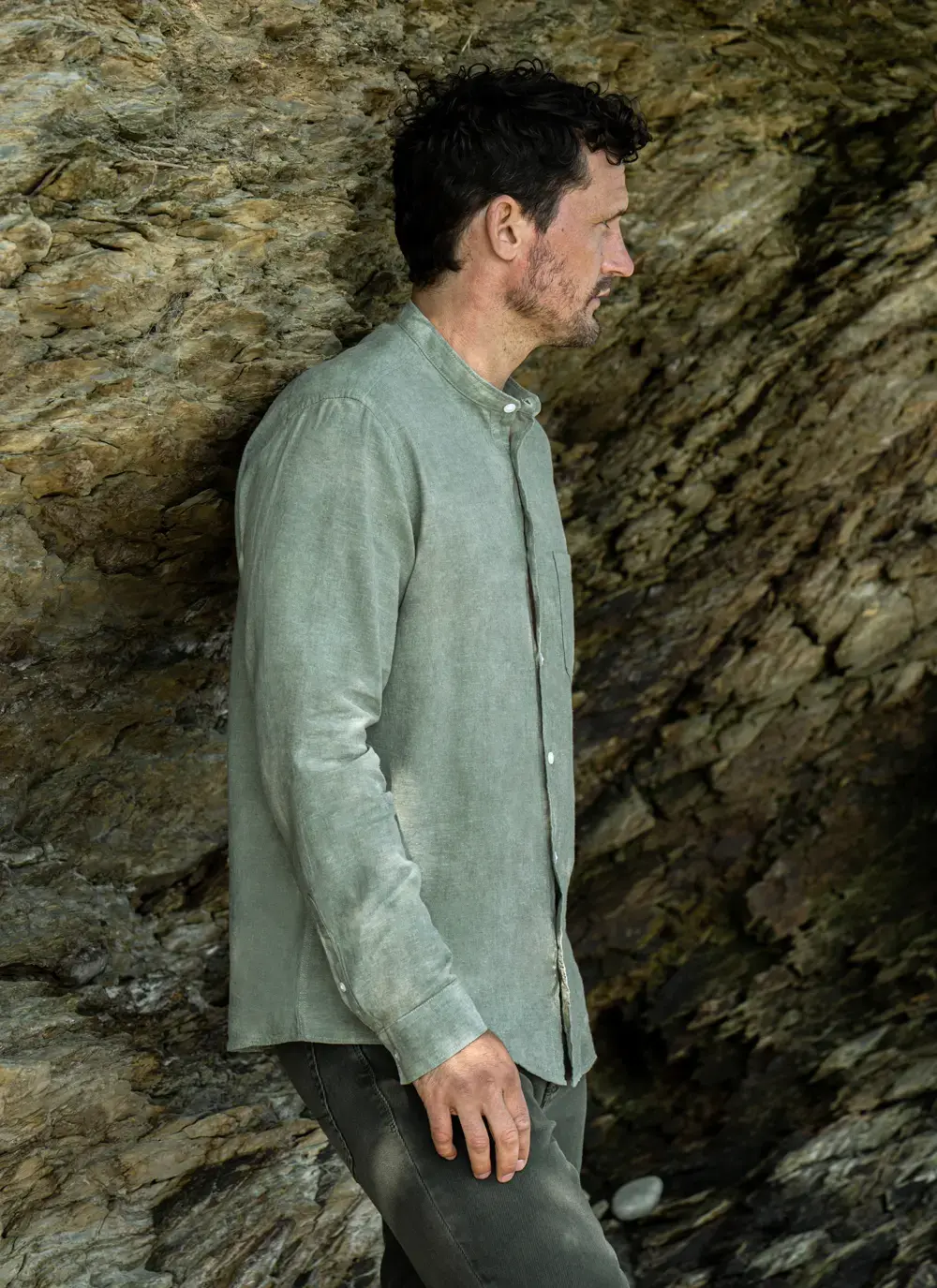 Donal cotton linen grandfather shirt in sage green, button-down front, lightweight and breathable, worn against rocky coastal backdrop
