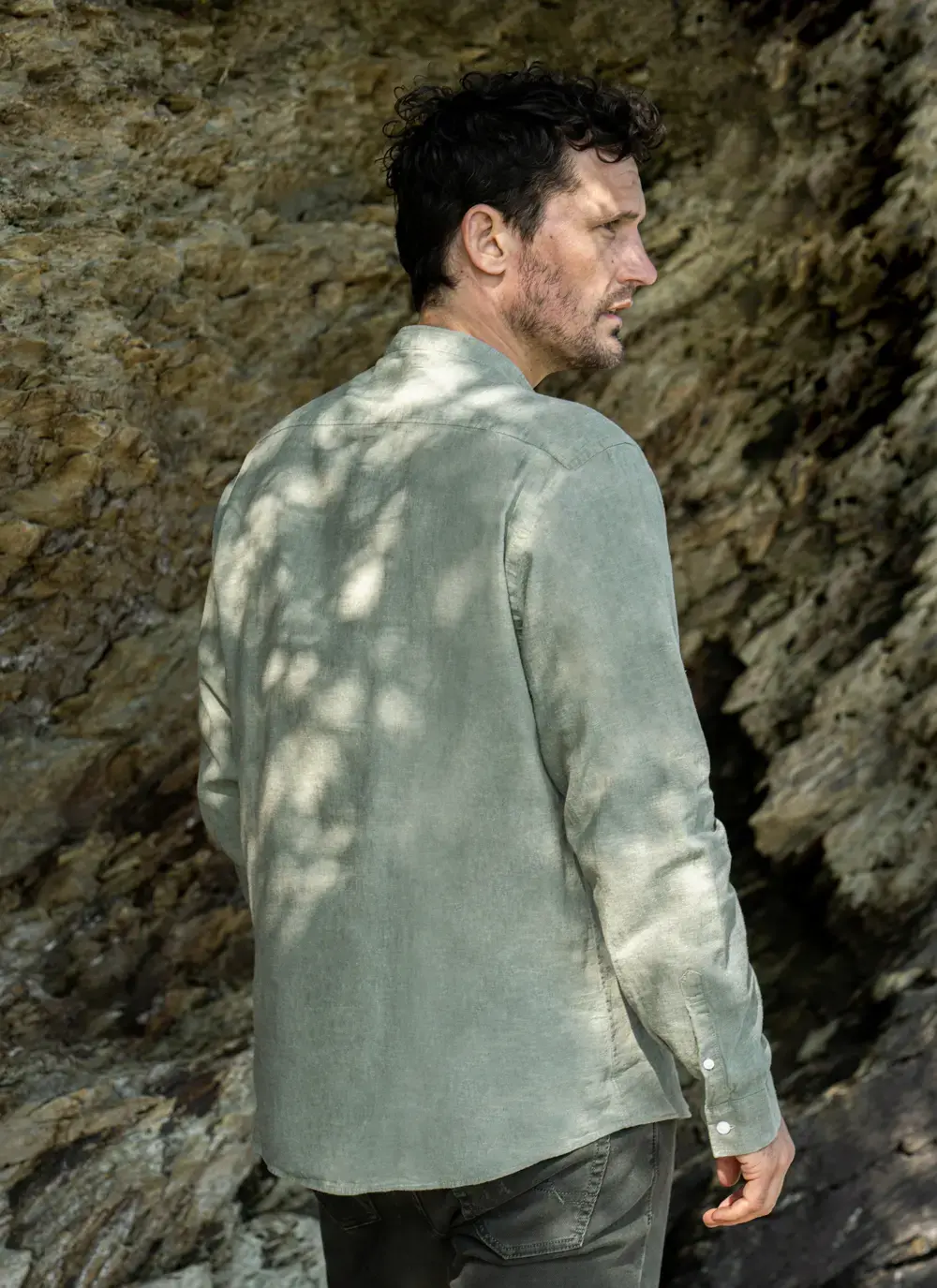 Donal cotton linen grandfather shirt in sage green, button-down front, lightweight and breathable, worn against rocky coastal backdrop