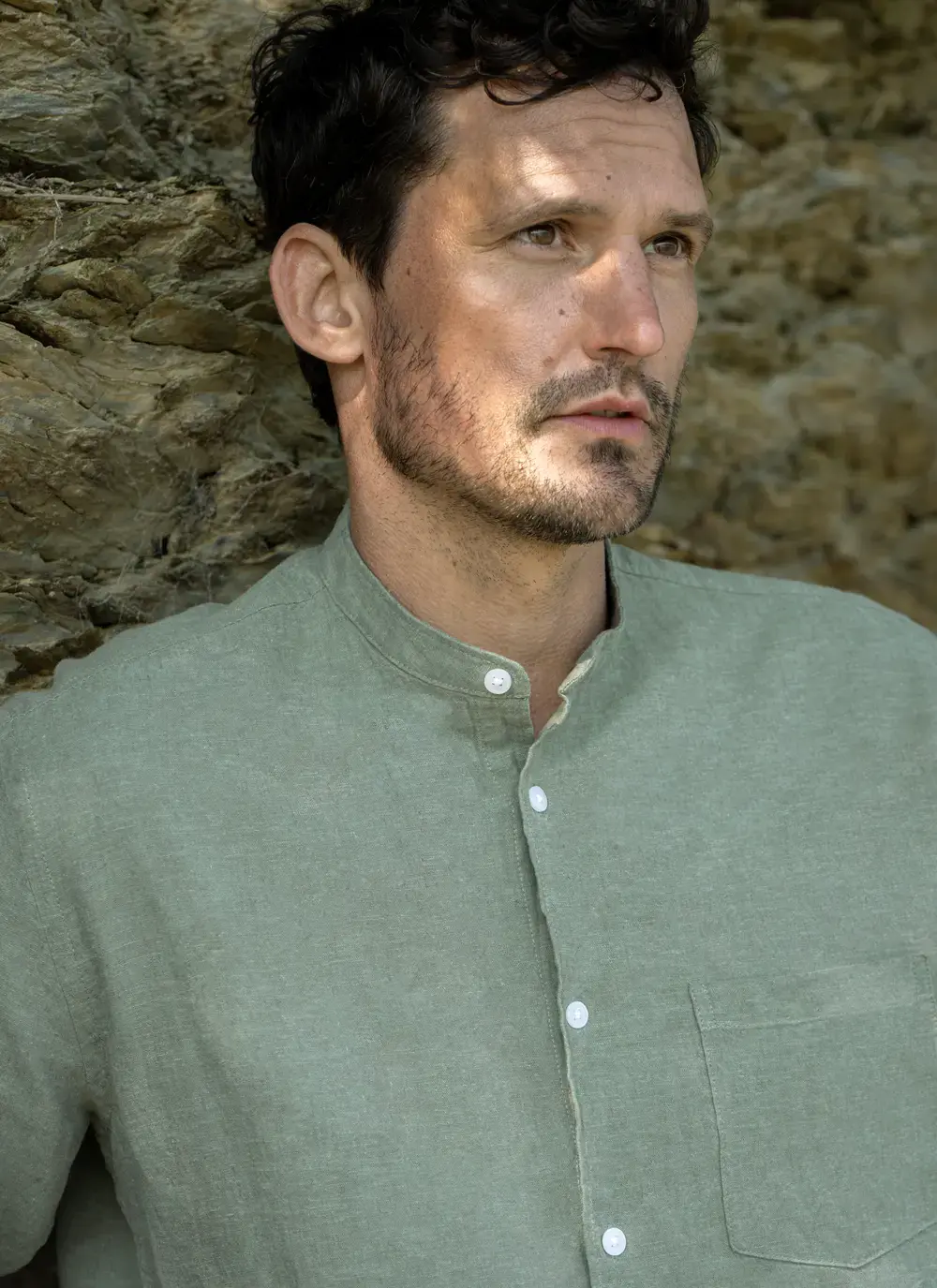 Donal cotton linen grandfather shirt in sage green, button-down front, lightweight and breathable, worn against rocky coastal backdrop