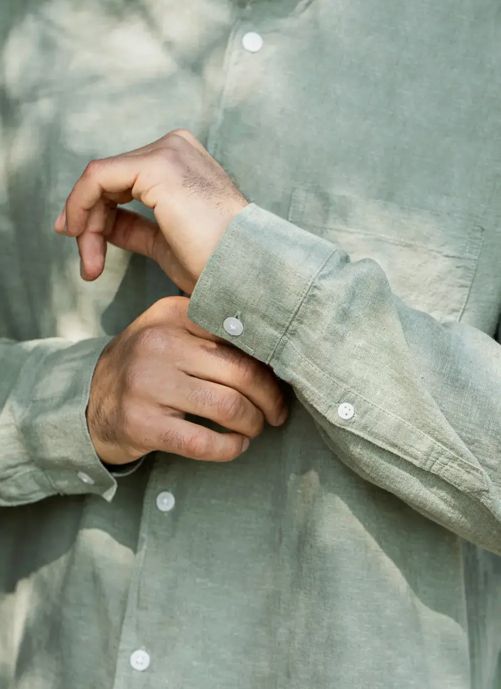 Donal cotton linen grandfather shirt in sage green, button-down front, lightweight and breathable, worn against rocky coastal backdrop