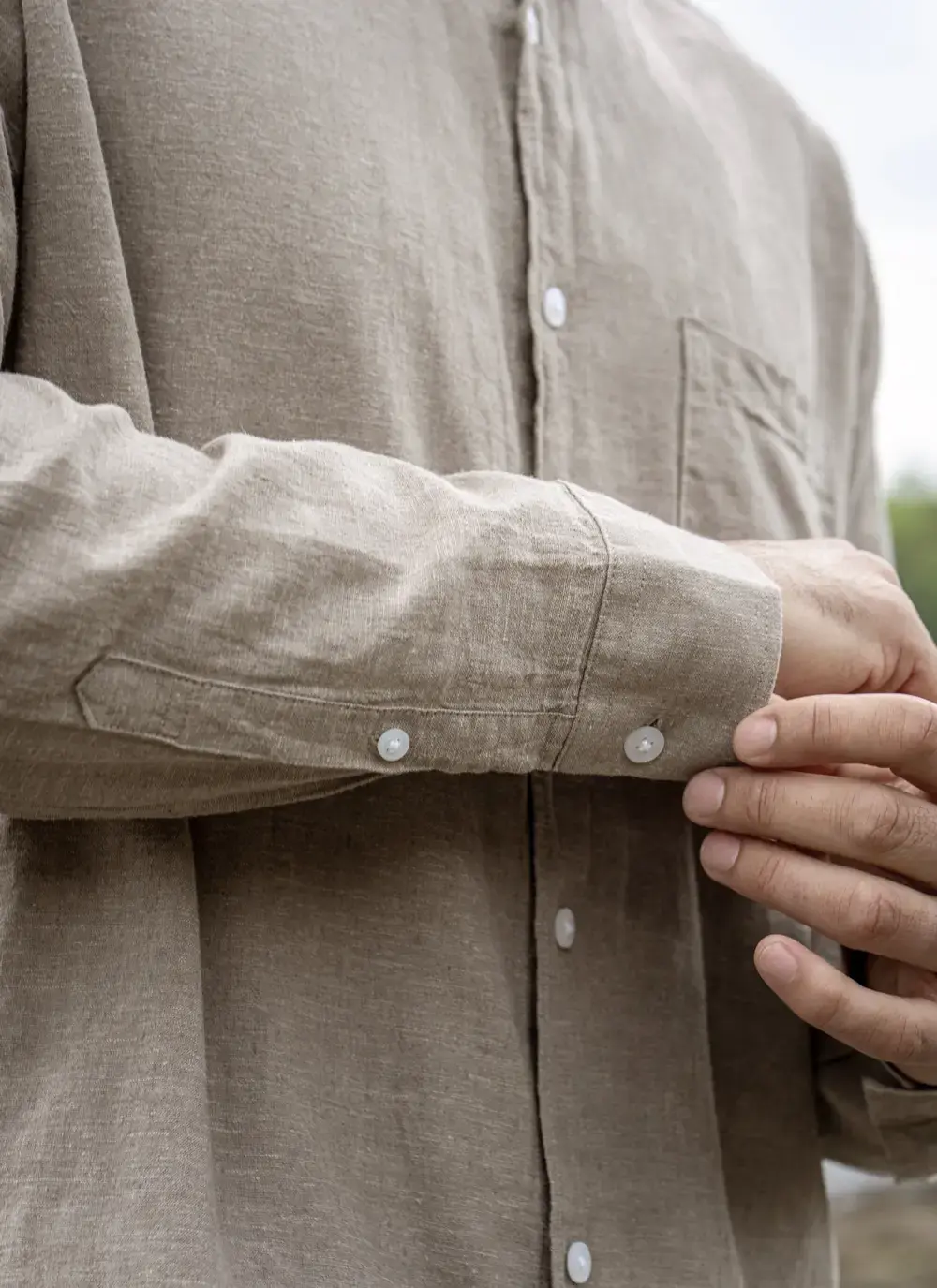 Model wearing Donal Cotton Linen Grandfather Shirt front-on, standing against a rugged stone backdrop in outdoor natural light.