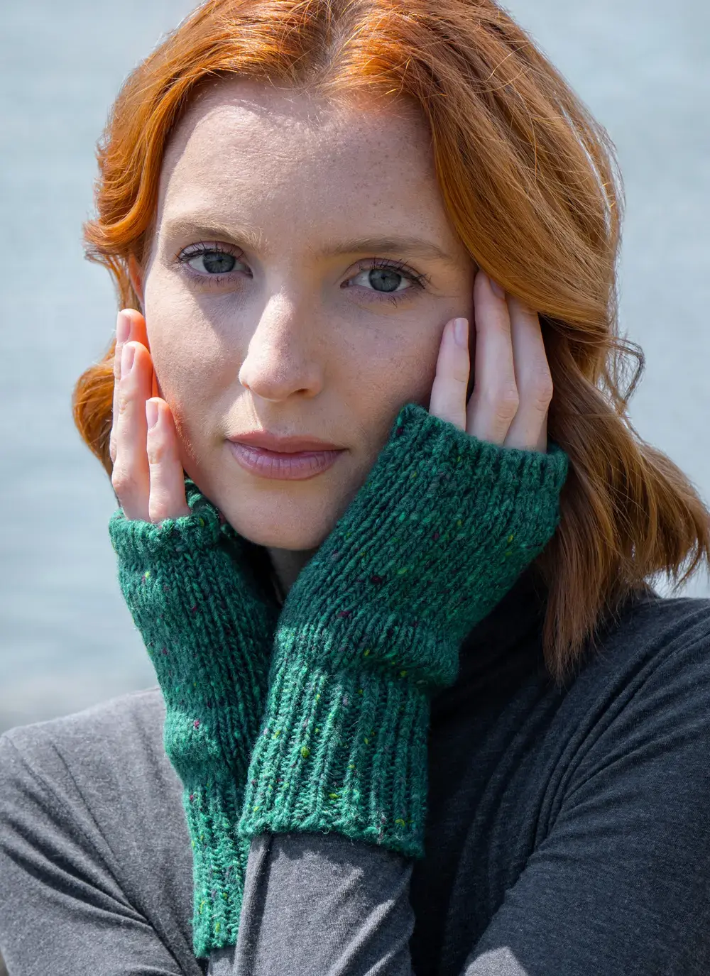 Red head model with head in hands wearing Donegal Tweed Handwarmers in Jade Green Color