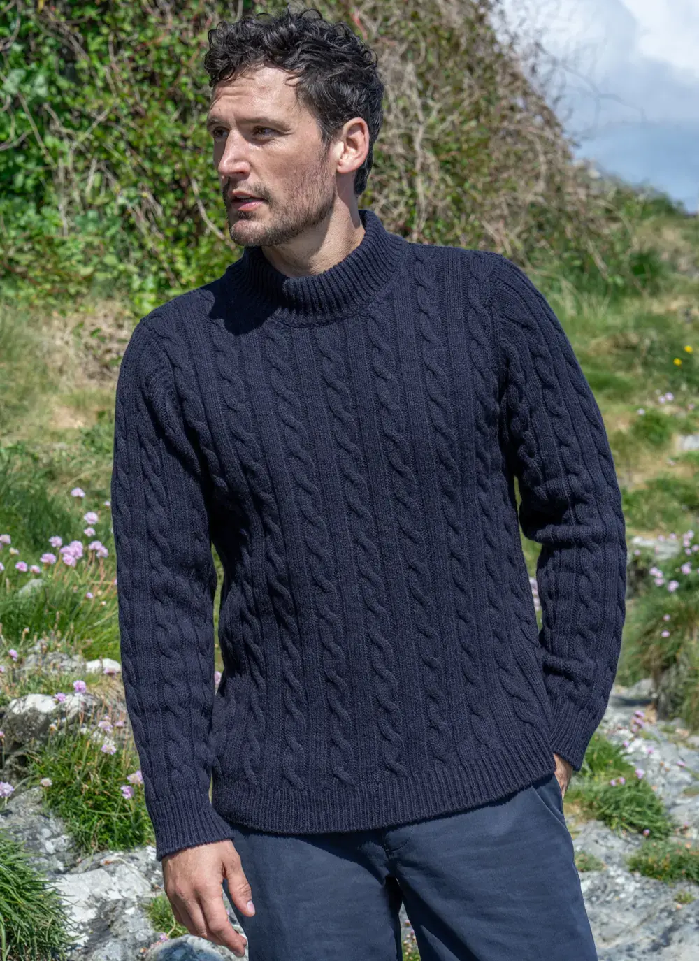 Front-facing view of Fisherman Cashmere Wool Sweater in Navy, showing full cable knit pattern, styled with navy trousers.
