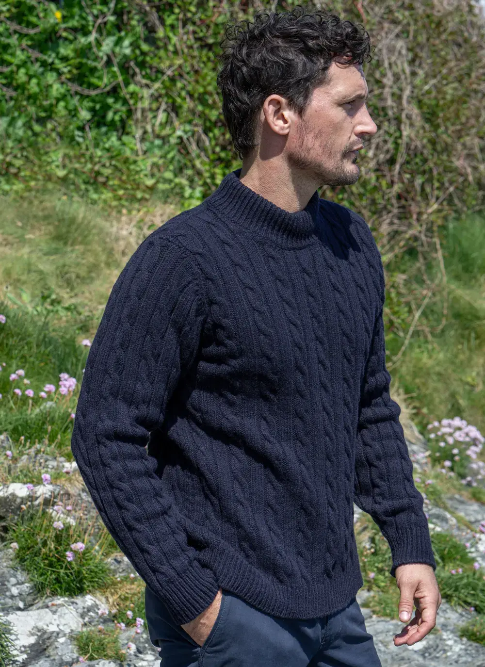 Side view of model wearing Navy Fisherman Cable Sweater, highlighting classic cable stitching and ribbed cuffs.