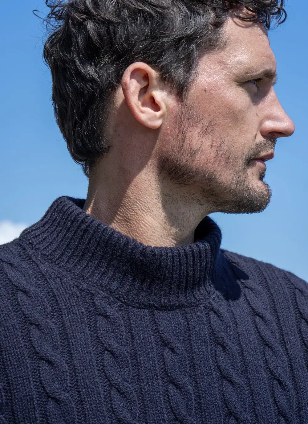 Close-up of neckline and cable knit texture on the Fisherman Sweater in Navy, set against clear blue sky.