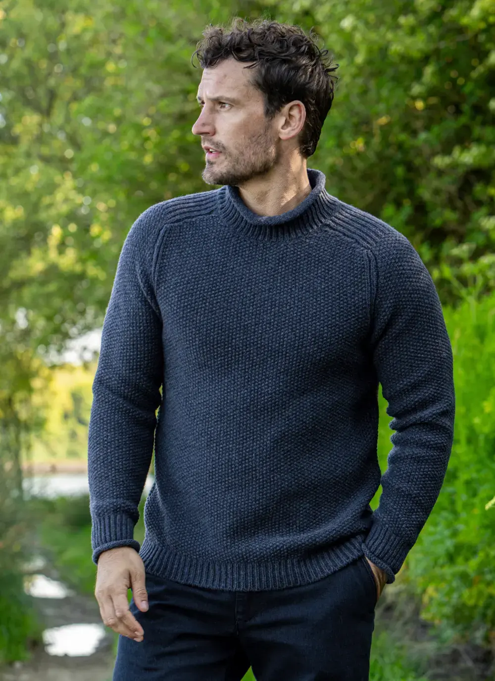 Model in Fisherman sweater looking into the distance with green background