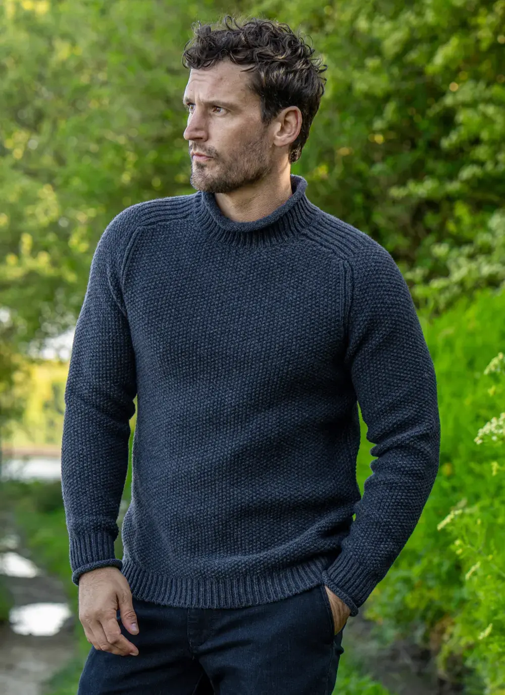 Model in Fisherman sweater looking into the distance with green background