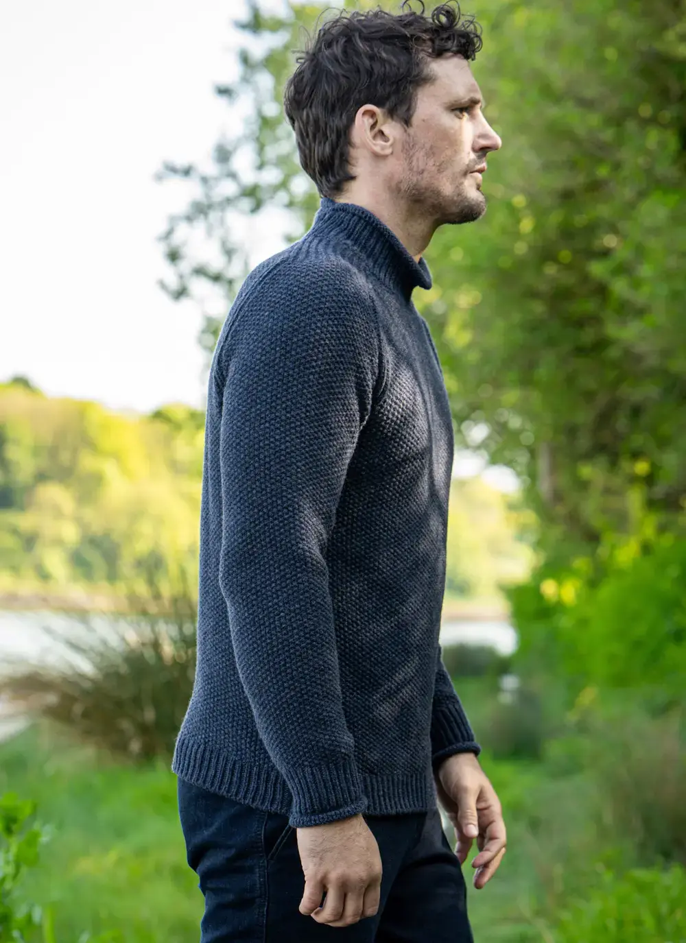 Side profile of the dark indigo Fisherman sweater showing roll neck and sleeve detail