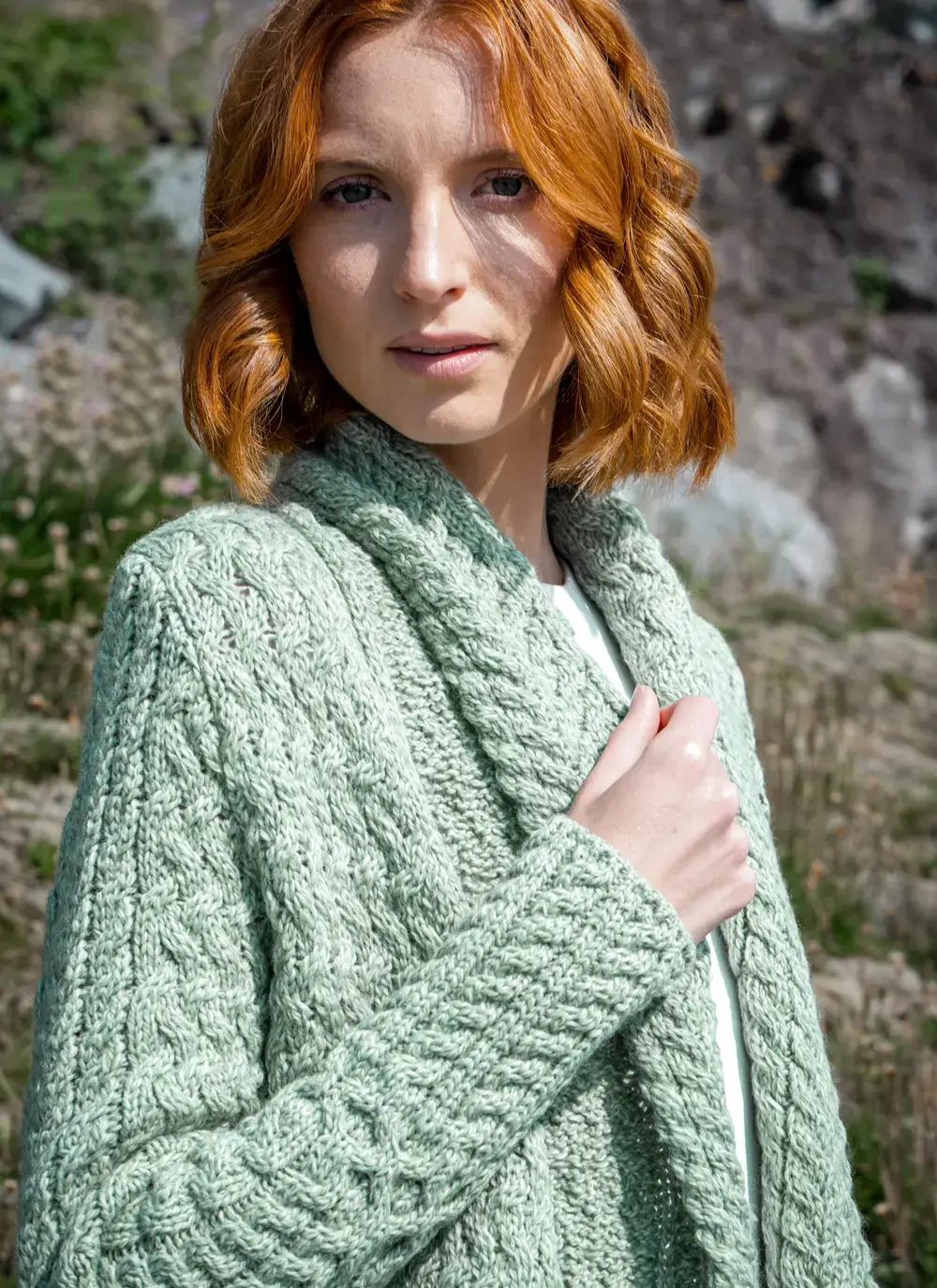Close up shot of model collar detail in front of rocky background glenross aran waterfall cardigan