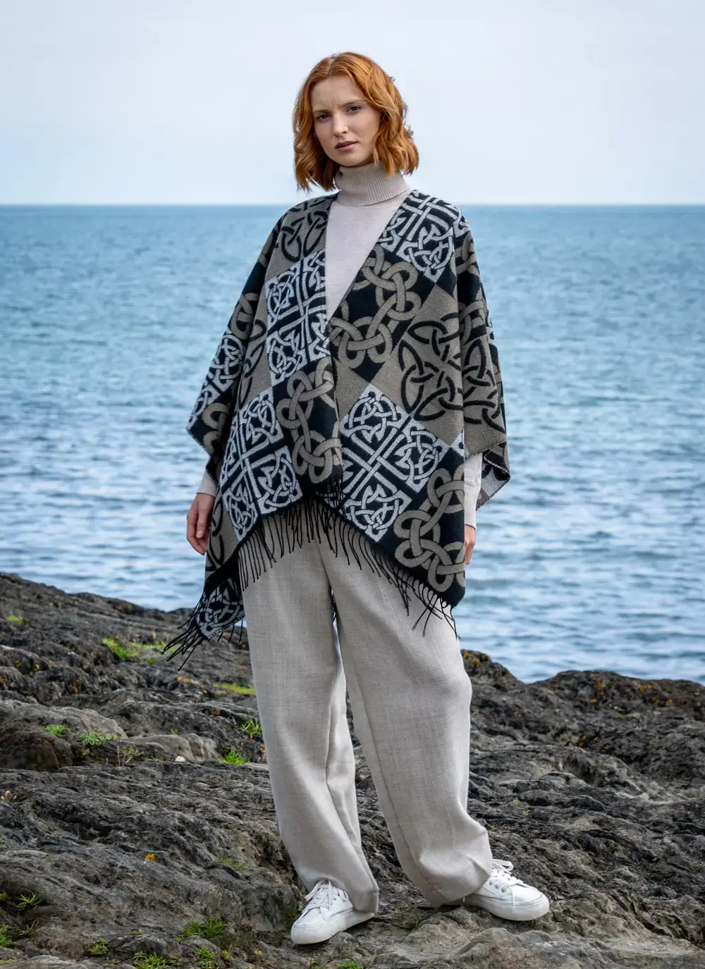 Red head model standing in front of water in black celtic knot shawl