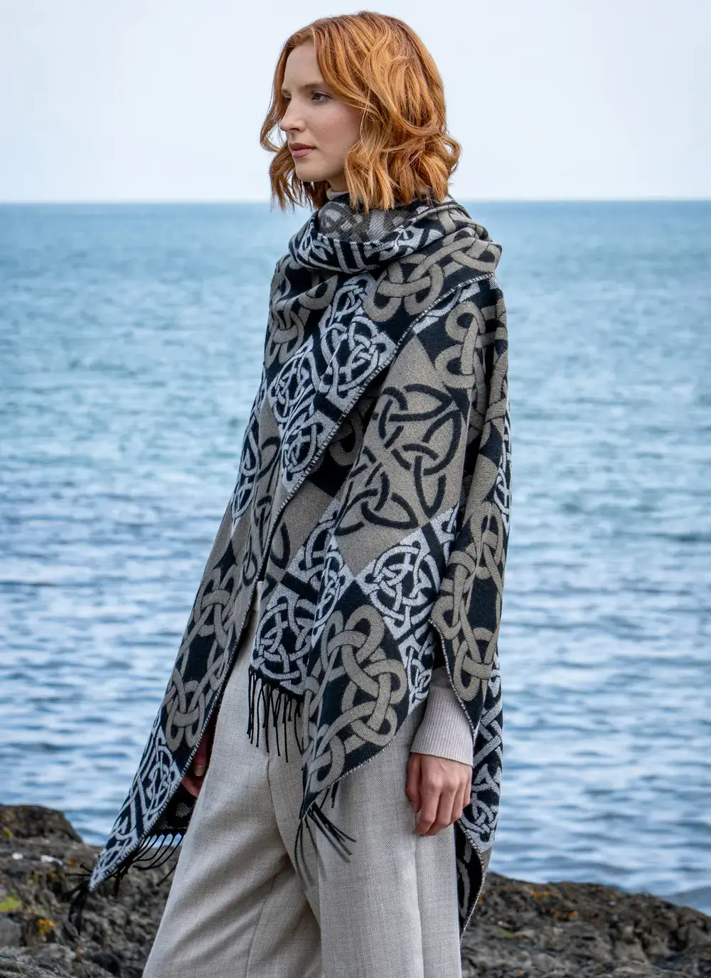 Red head model side view in front of water in black celtic knot shawl draped over shoulder