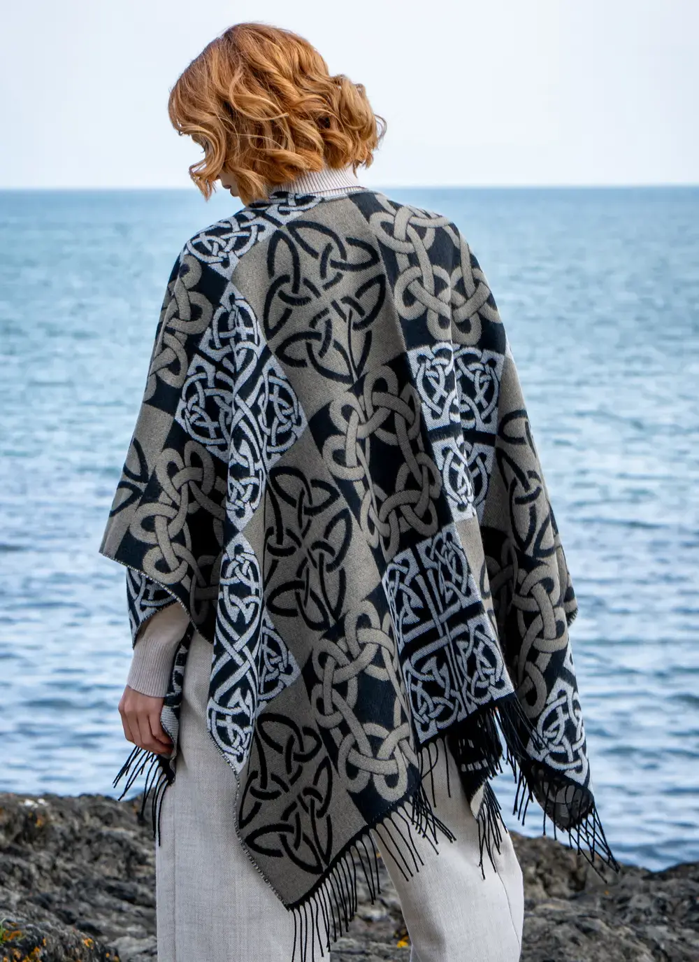 Red head model facing the water in black celtic knot shawl draped over shoulder back detail