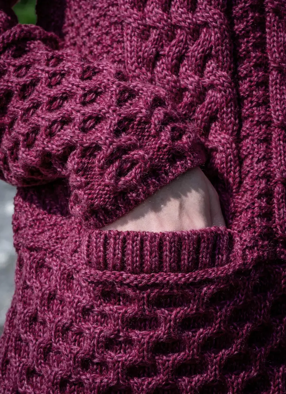 Close up of Red head model pocket detail grace full zip aran cardigan in raspberry melange