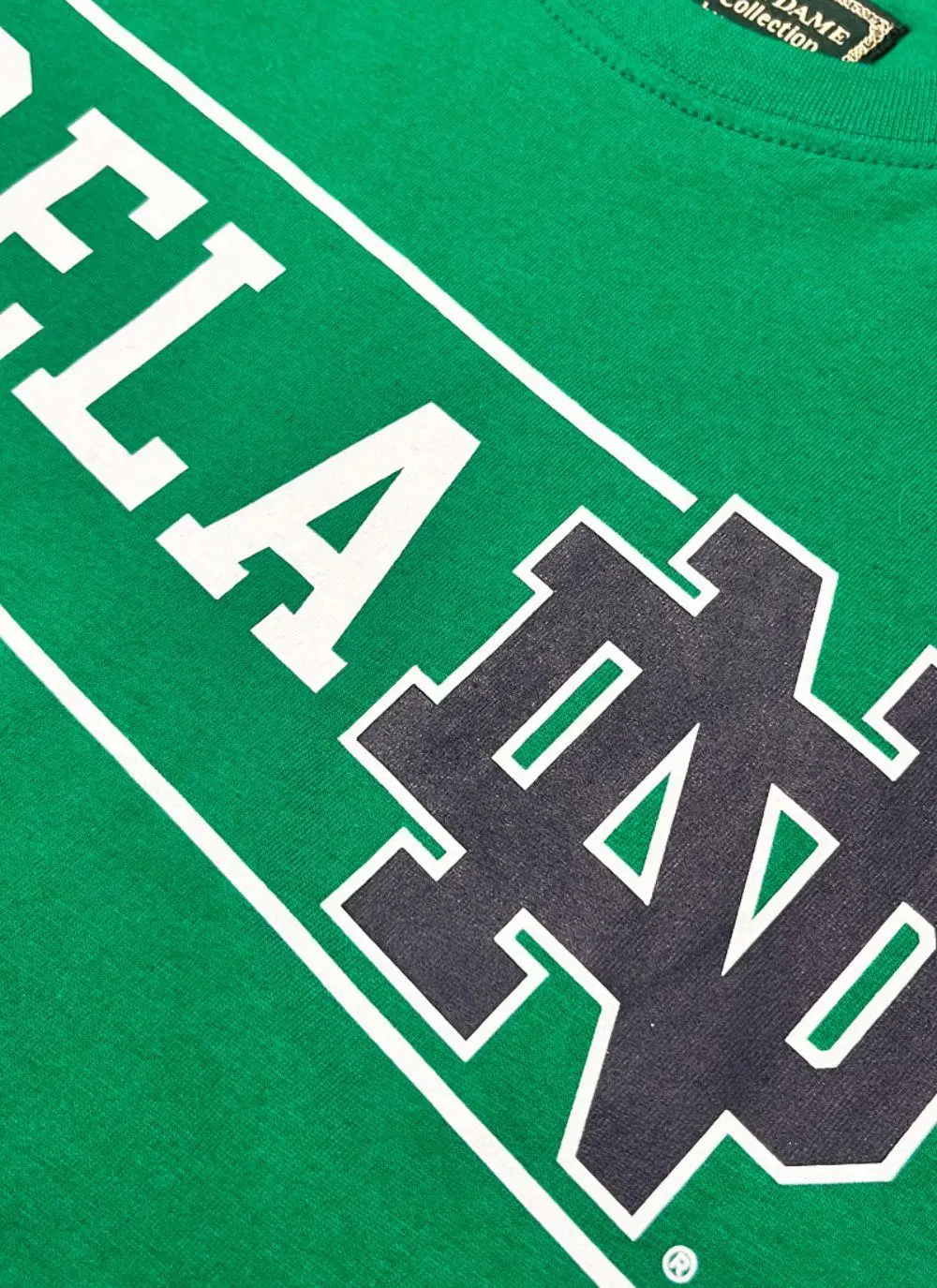 Green t-shirt with letters spelling Ireland and fighting Irish logo printed and a shamrock sewn in at the bottom