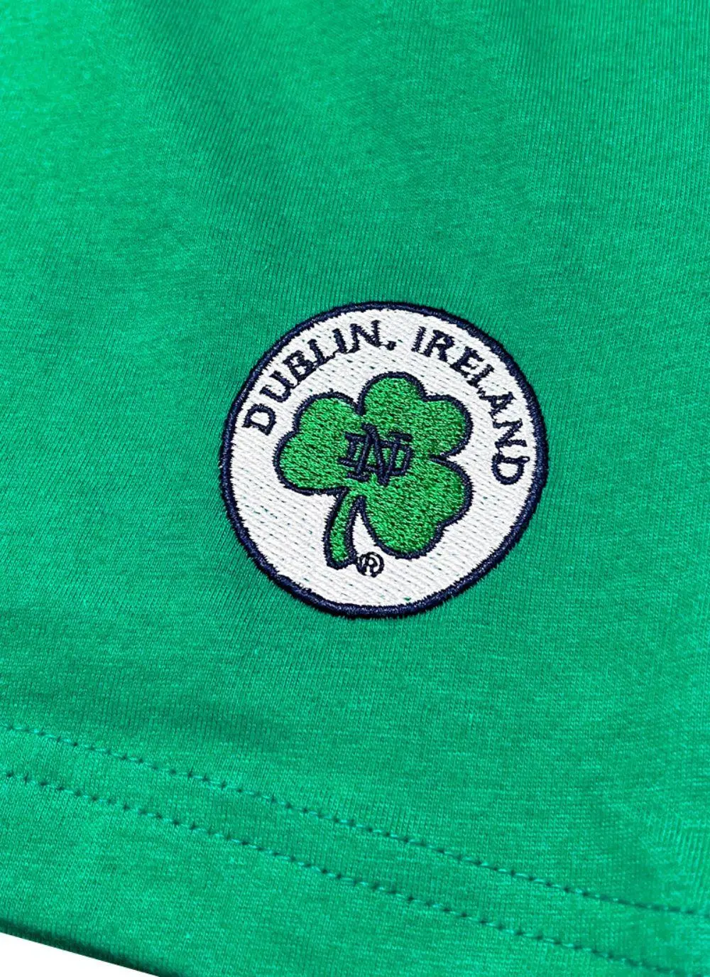 Green t-shirt with letters spelling Ireland and fighting Irish logo printed and a shamrock sewn in at the bottom