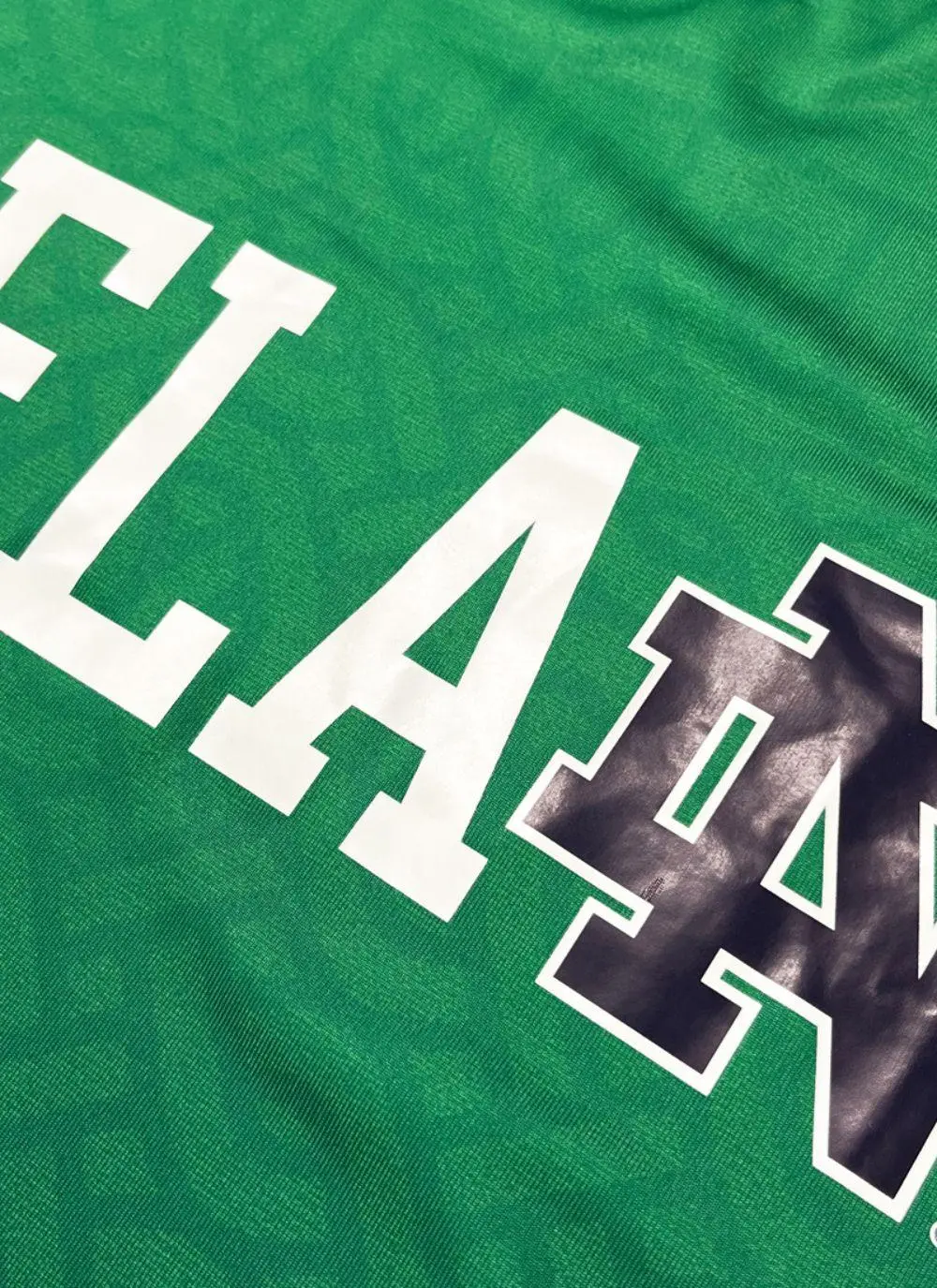Green t-shirt with letters spelling Ireland and fighting Irish logo printed, navy sleeves, celtic print all over