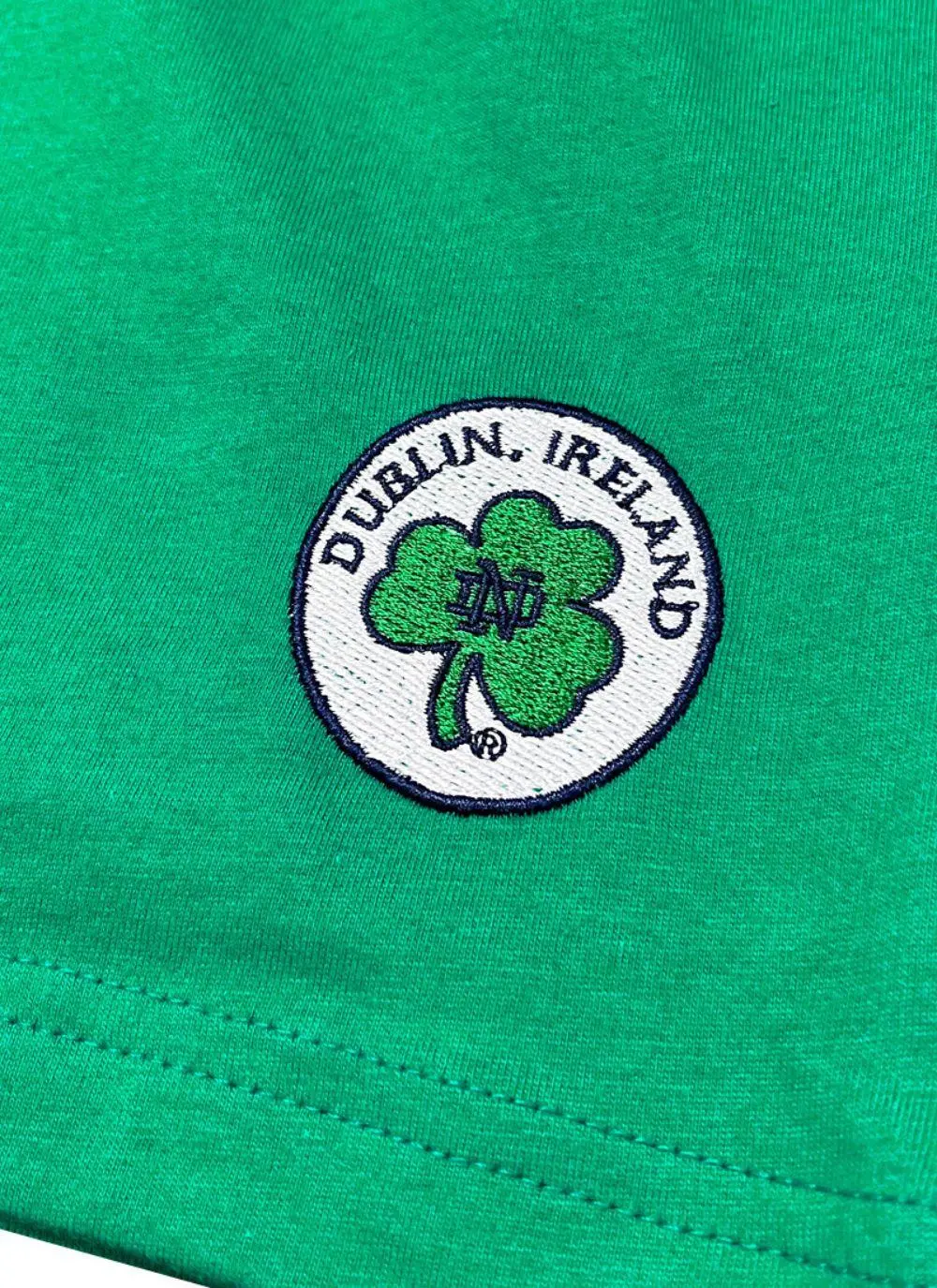Kids green t-shirt with letters spelling Ireland and fighting Irish logo printed and a shamrock sewn in at the bottom