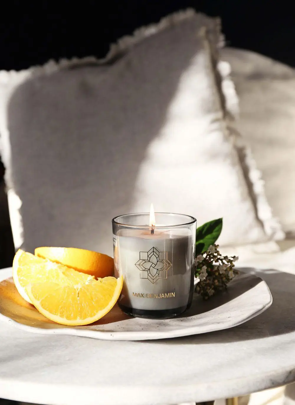 burning candle with oranges on table 