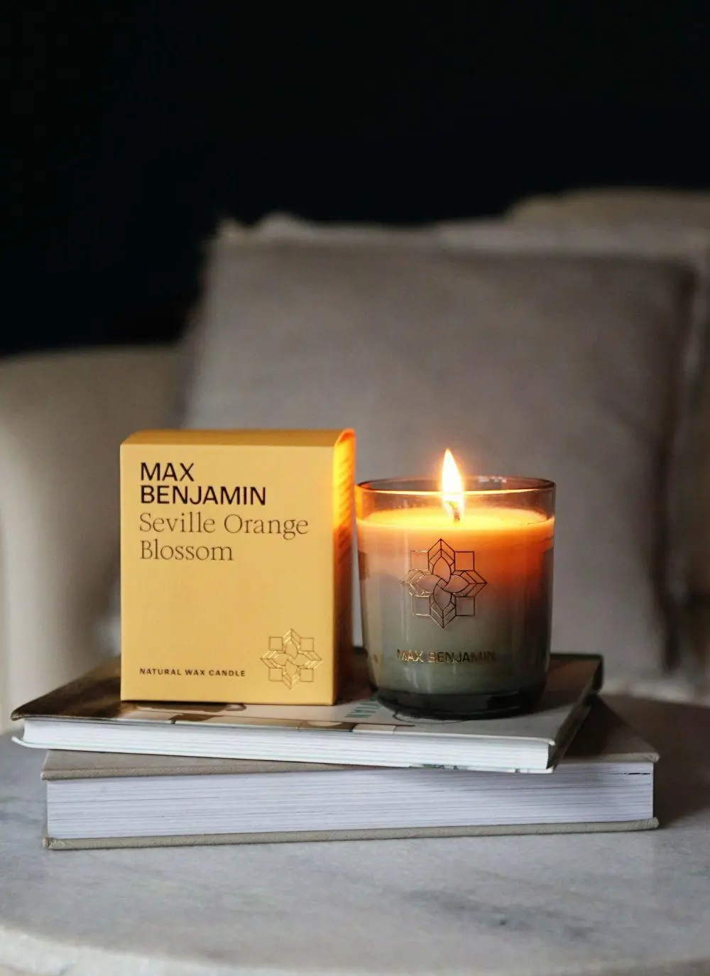 burning candle with packaging on books