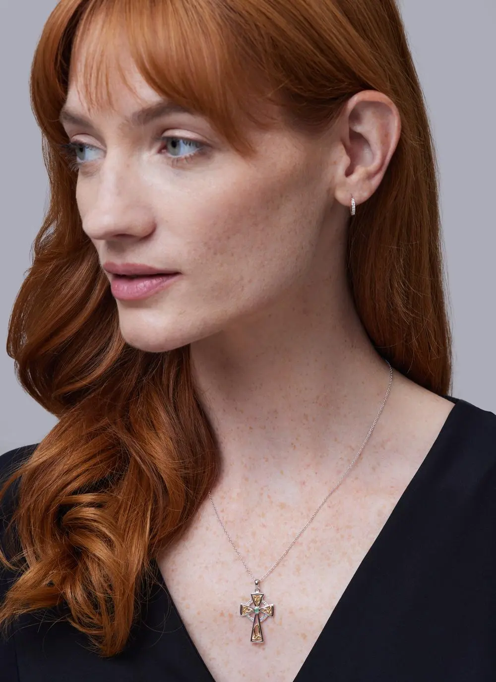 Red haired model wearing Silver Celtic Trinity Diamond And Emerald Cross Pendant