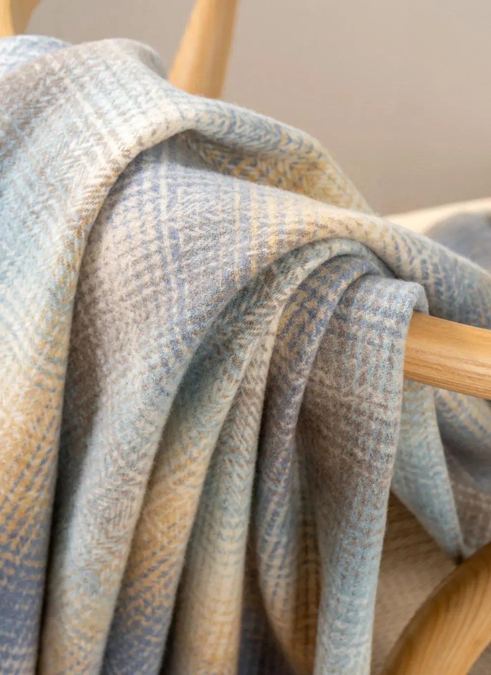 Blue and beige lambswool throw draped across wooden chair
