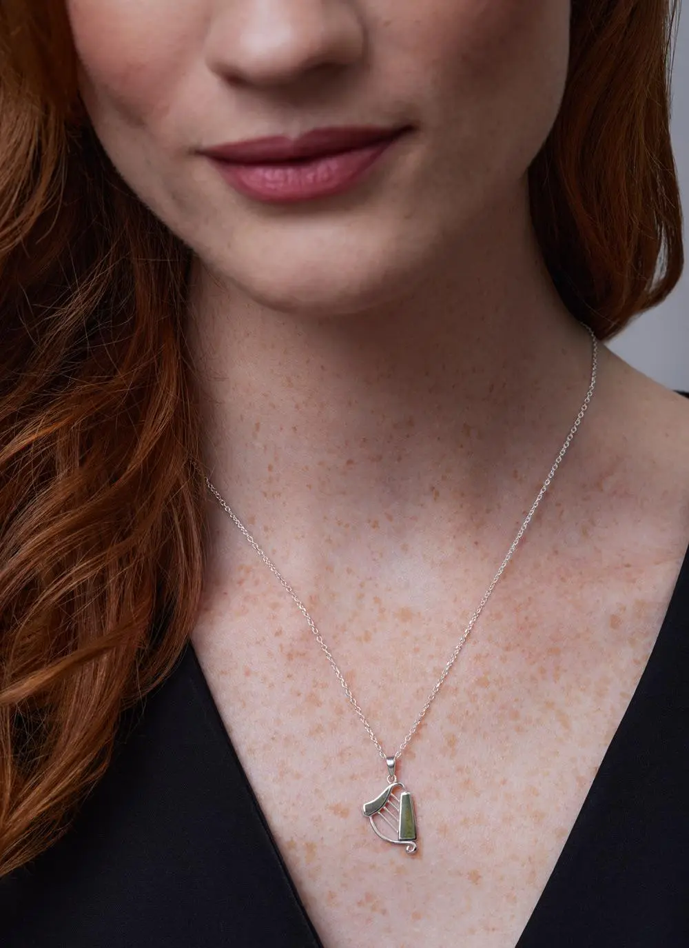 Close up shot of red haired model wearing Sterling Silver Connemara Marble Harp Pendant