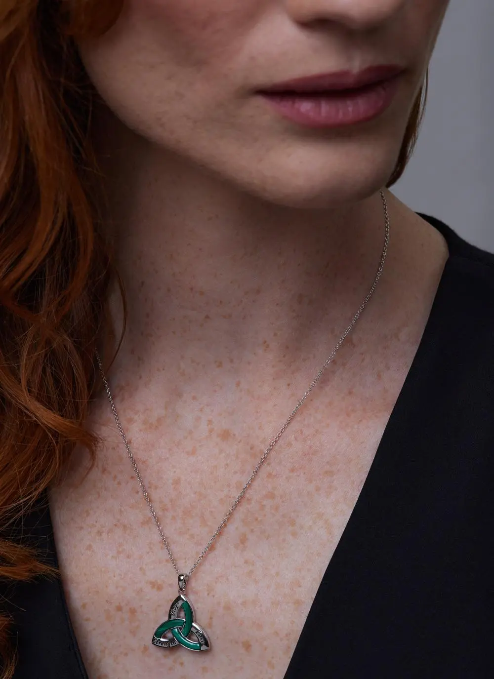 Close up of red haired model wearing Sterling Silver Malachite Trinity Knot Pendant