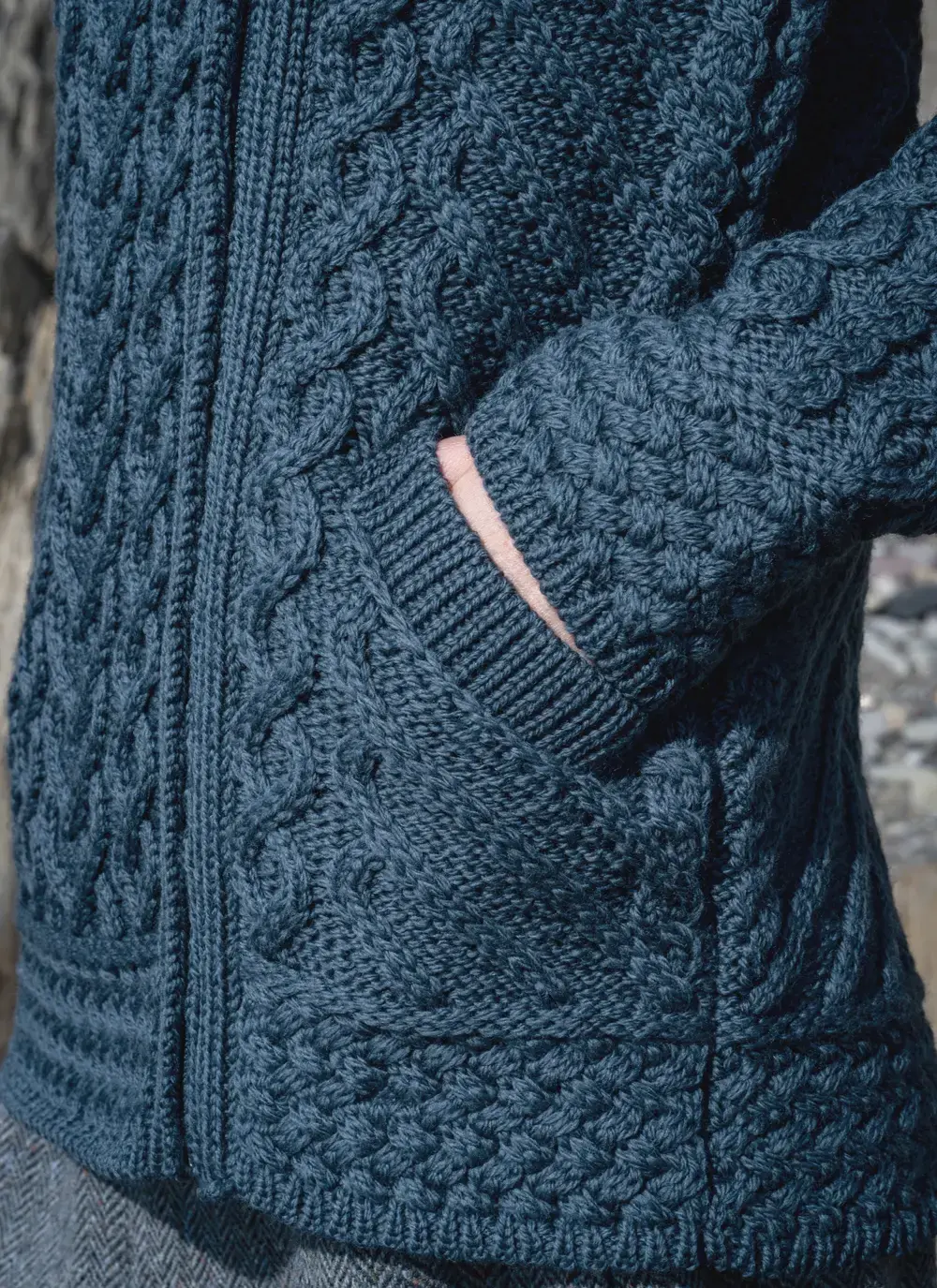 Close up of red headed model sleeve detail blue aran biker hoodie hand in pocket