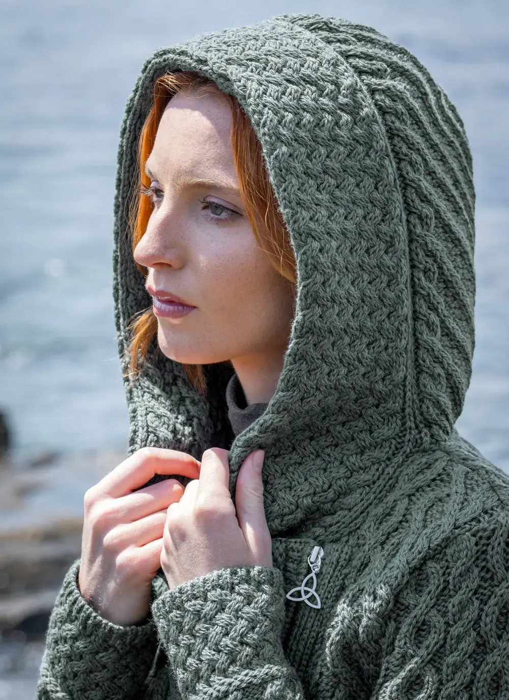 Close up of red head model with sea background detail of hood tundra aran cable knit biker hoodie