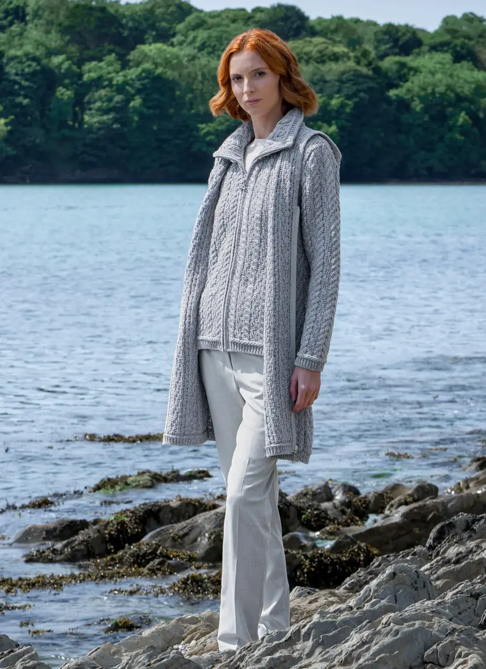 redhead woman on rocky beach wearing closed long grey aran coatigan 