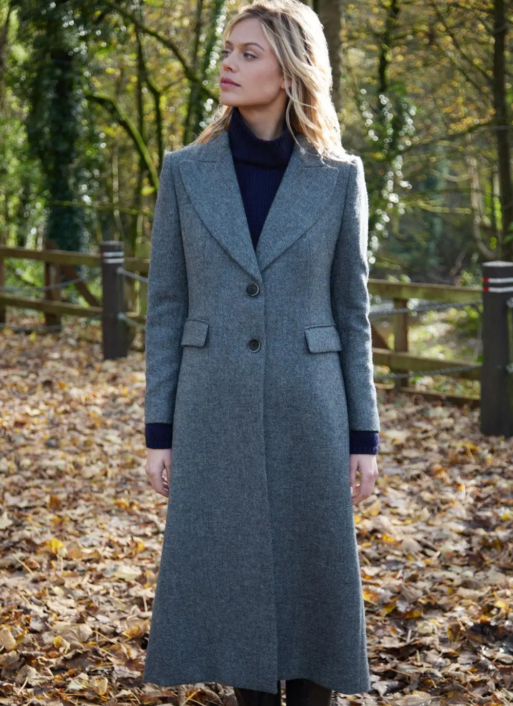 Blonde woman in woodland area wearing longline blue herringbone tweed coat
