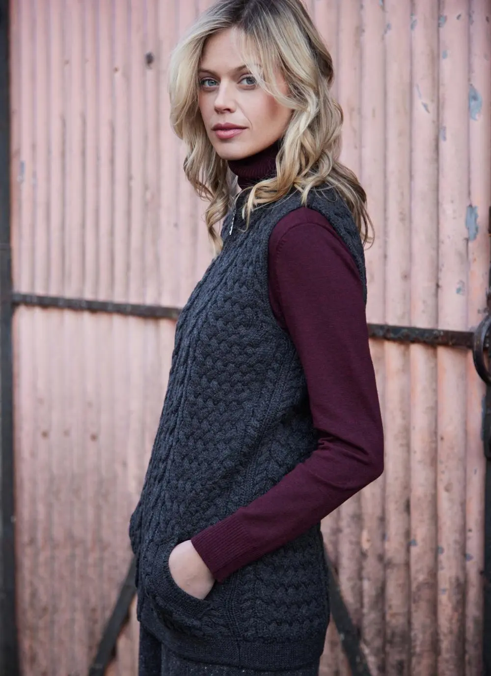 Women standing in front of pink door wearing charcoal aran gilet