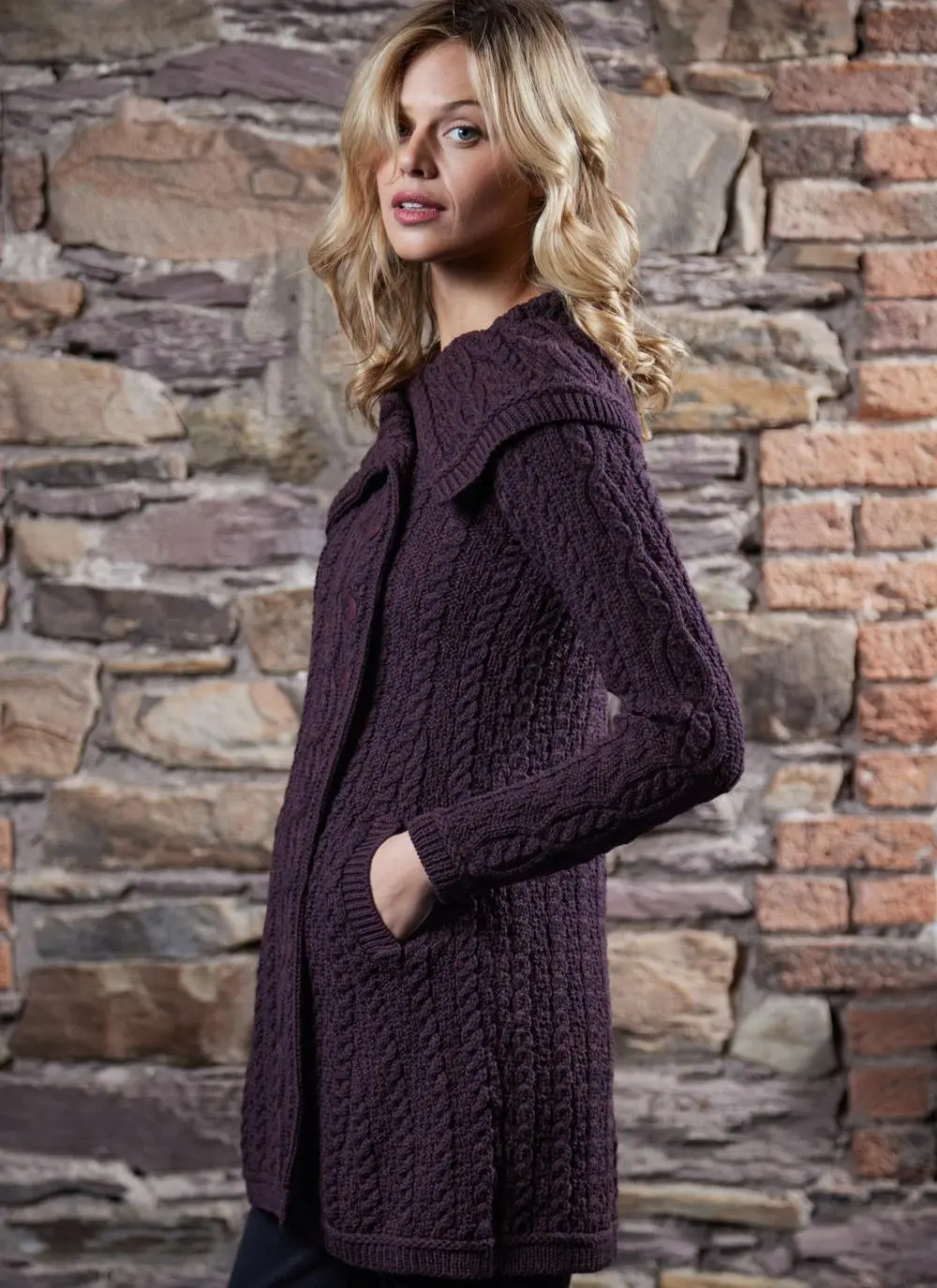 studio shot of blonde woman wearing dark purple aran long aran cardigan