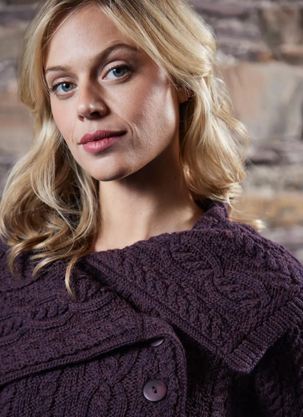 studio shot of blonde woman wearing dark purple aran long aran cardigan