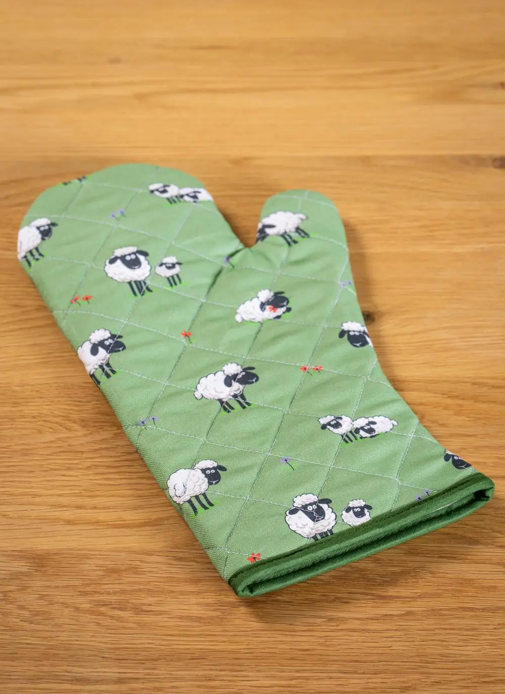 green gauntlet with sheep motif on tabletop